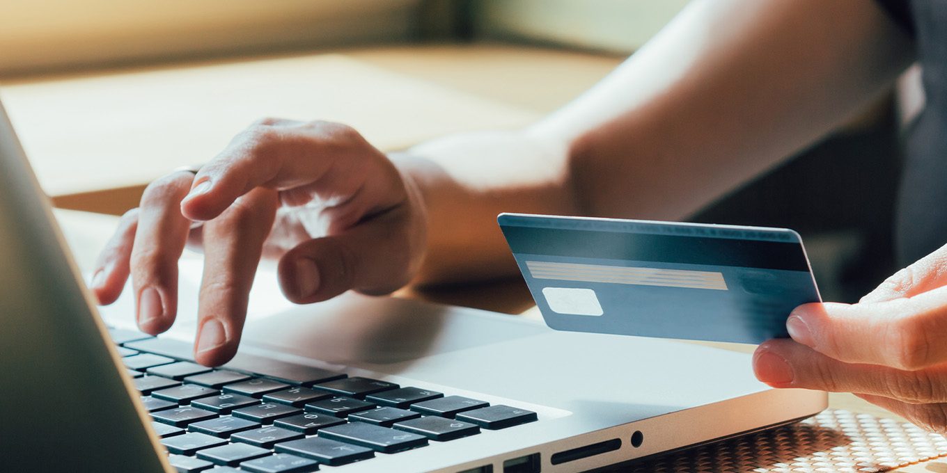 person holding credit card in front of laptop